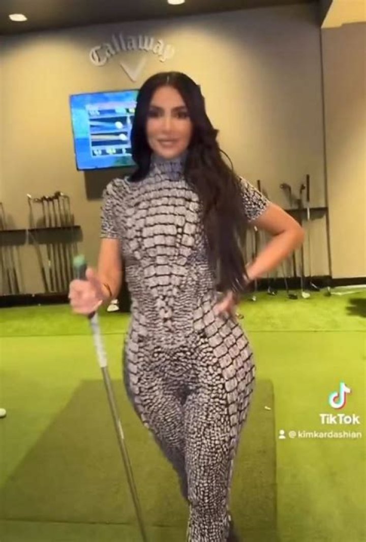 Kim Kardashian sticks out famous butt in tight snakeskin catsuit for new video as she plays mini gol
